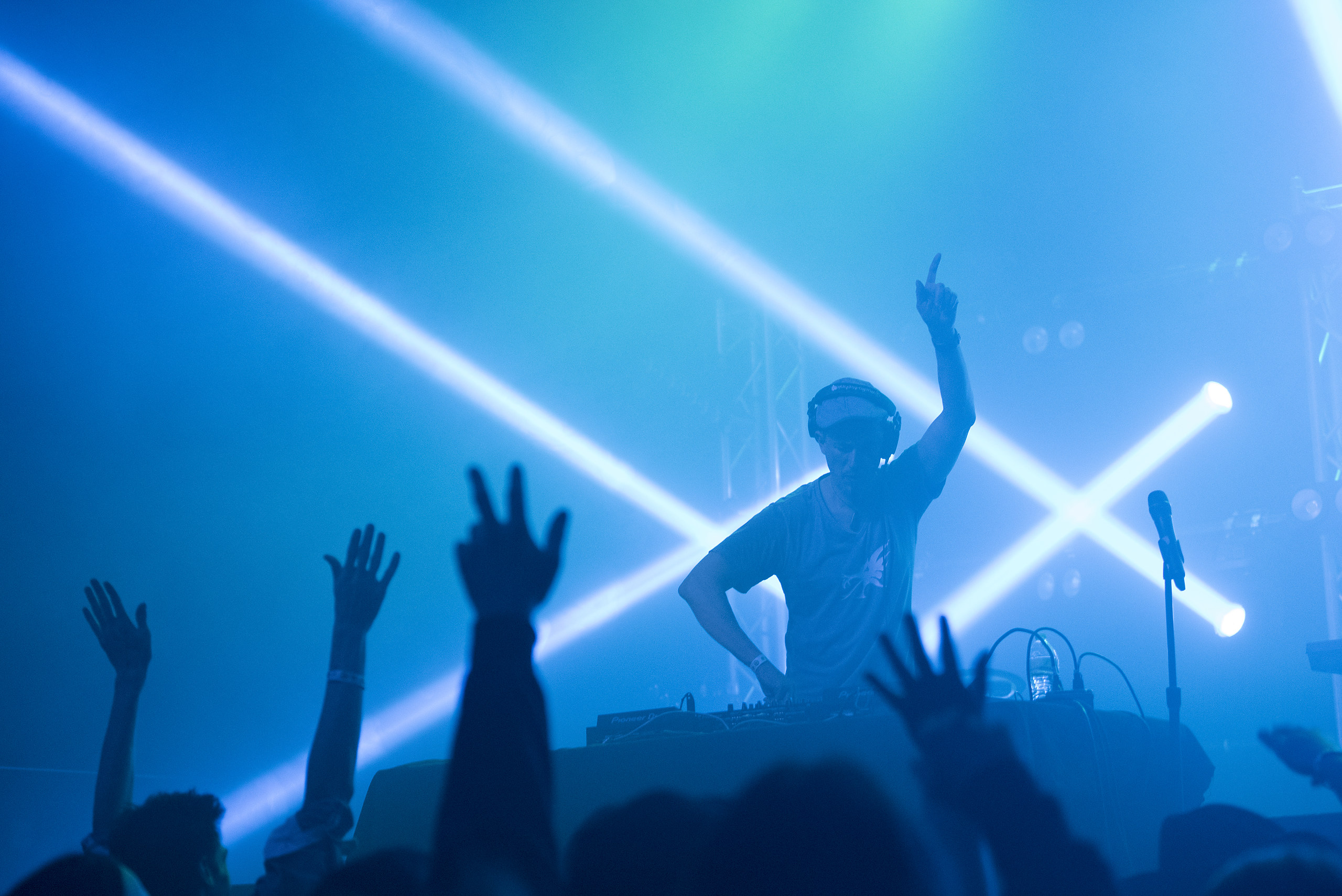 Concert crowd with hands raised under blue laser light