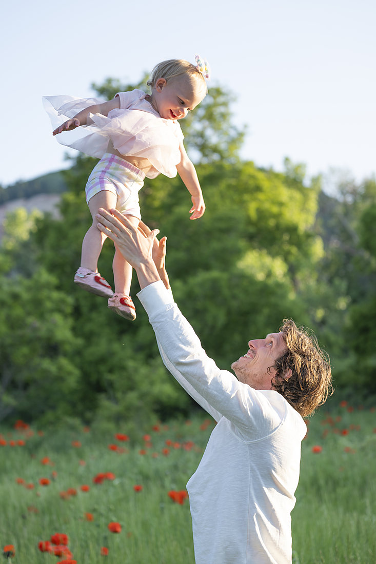 Father tossing his child in the air at sunset