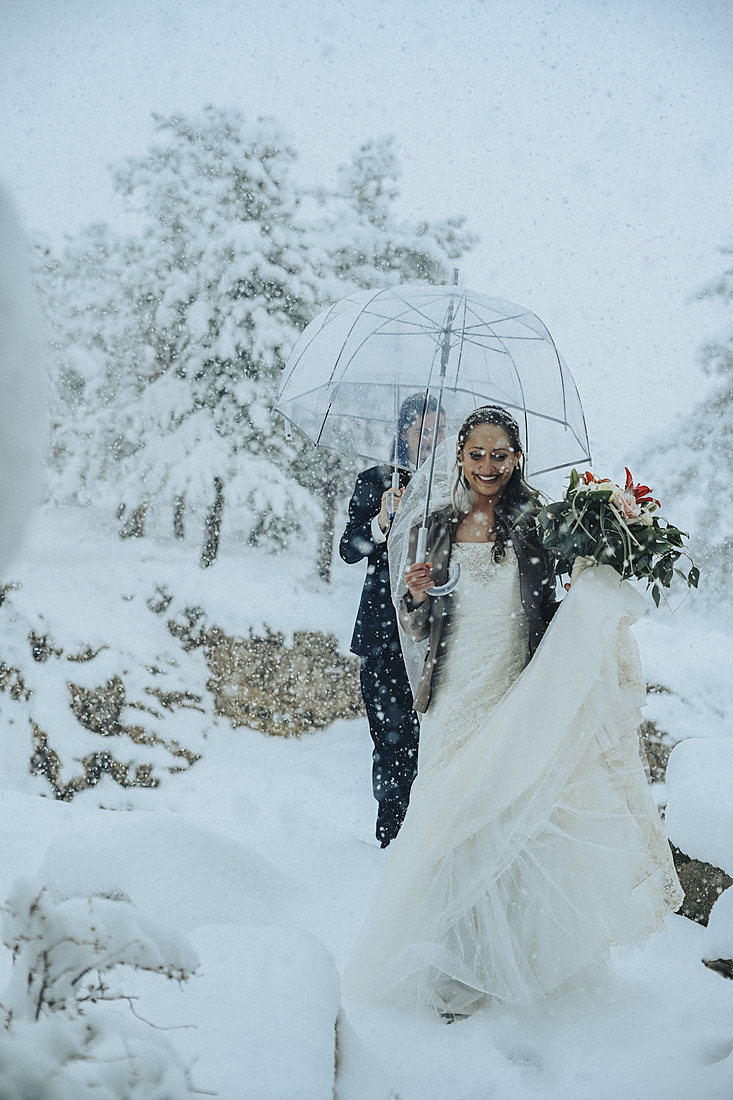 Couple walking through falling snow on their wedding day